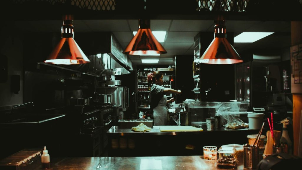 Keukenmedewerker werkt in restaurantkeuken na sluitingstijd met apparatuur en voorbereidingen
