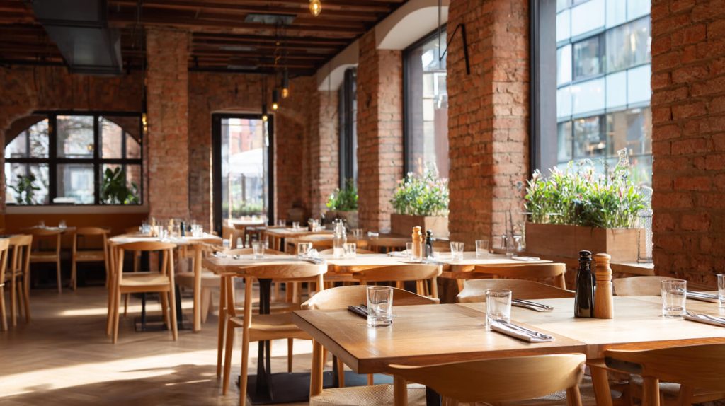 Sfeervol ingericht restaurant met bakstenen wanden en houten tafels na de horecaverbouwing